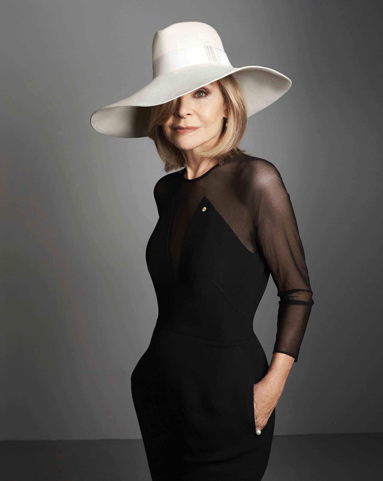 Fashion designer Carla Zampatti wearing a black dress and white hat.