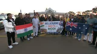 A group of people outside holding a sign saying Melbourne Meets Modi.