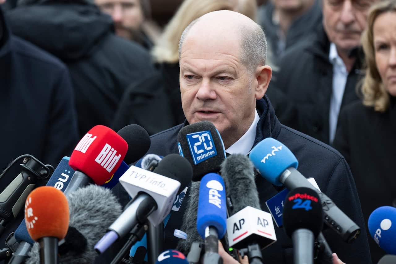 Olaf Scholz in front of several press microphones.