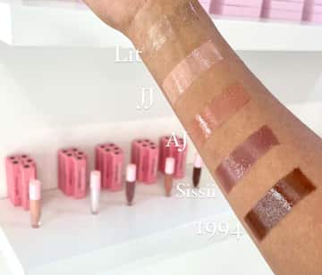 An outstretched forearm with four different shades of lip gloss on it, ranging from nude through tan and into rich dark brown