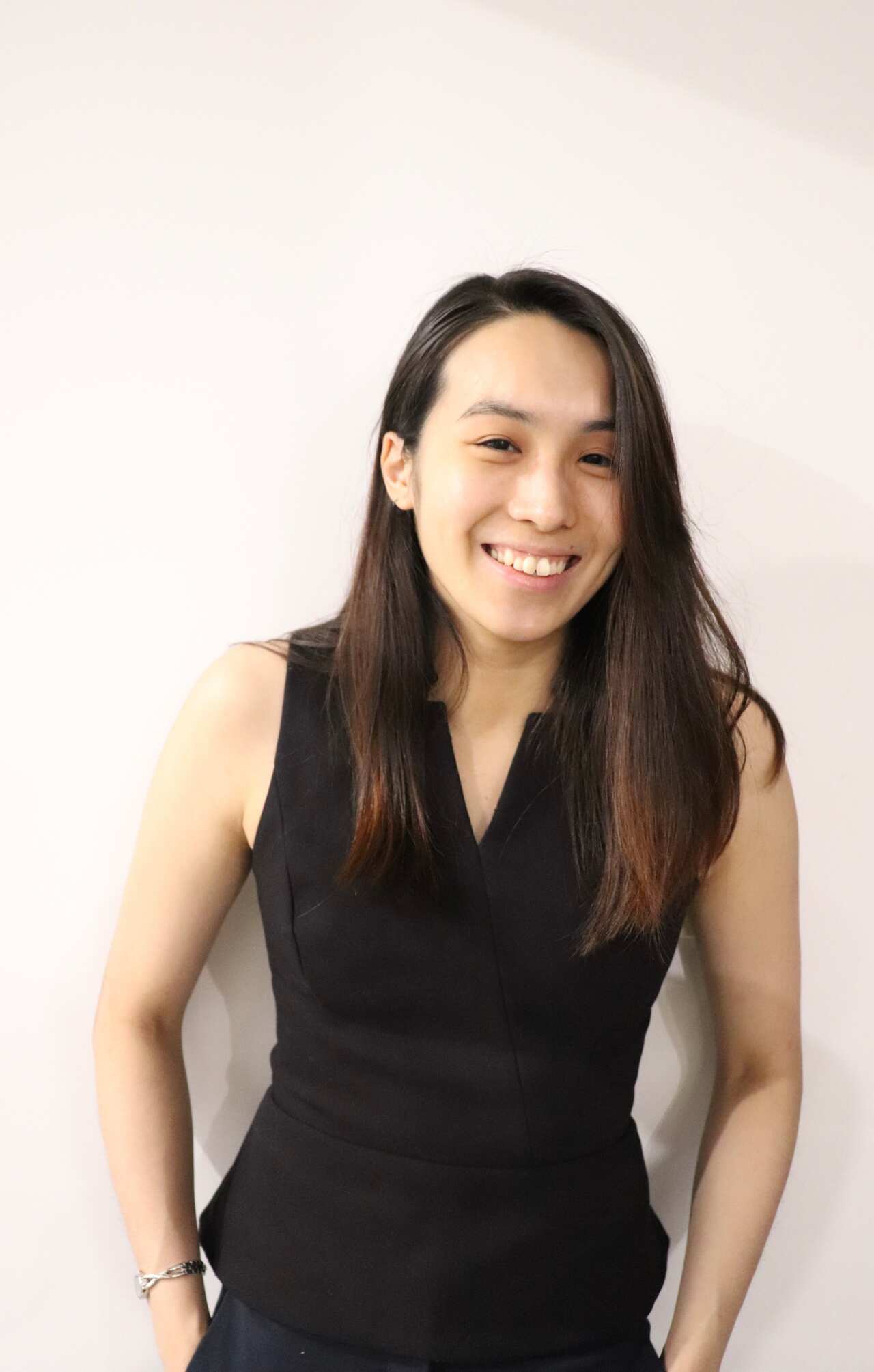A woman in a black dress and long dark hair smiles at the camera.