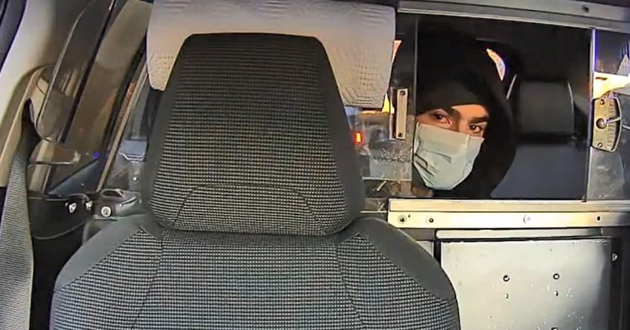 A handout photo issued by the New York City police department shows a person wearing a hoodie and a mask inside a car.