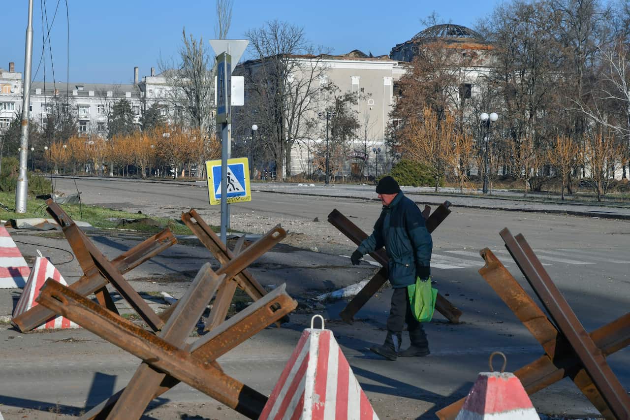 A man walking along a street that is partly barricaded. 