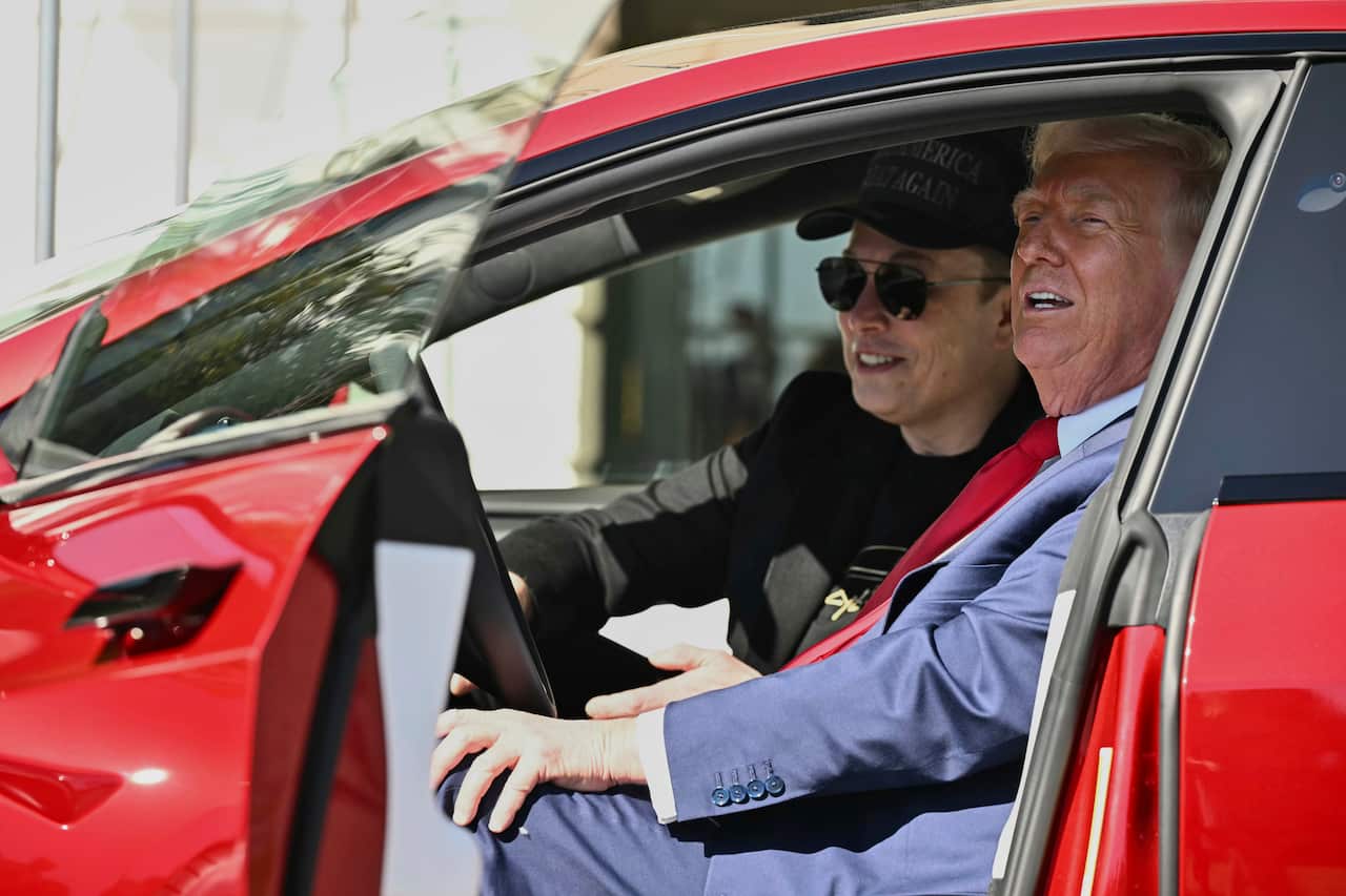 Elon Musk and Donald Trump, sitting in a red car, with the door open.