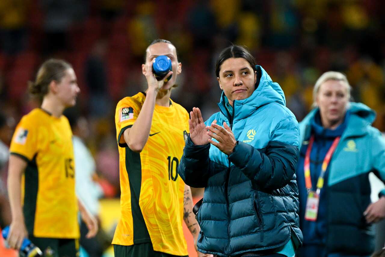 Woman in blue puffy jacket claps while looking downcast.