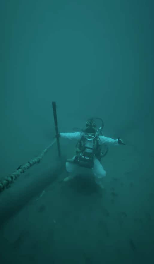 A commercial diver stands on the ocean floor.