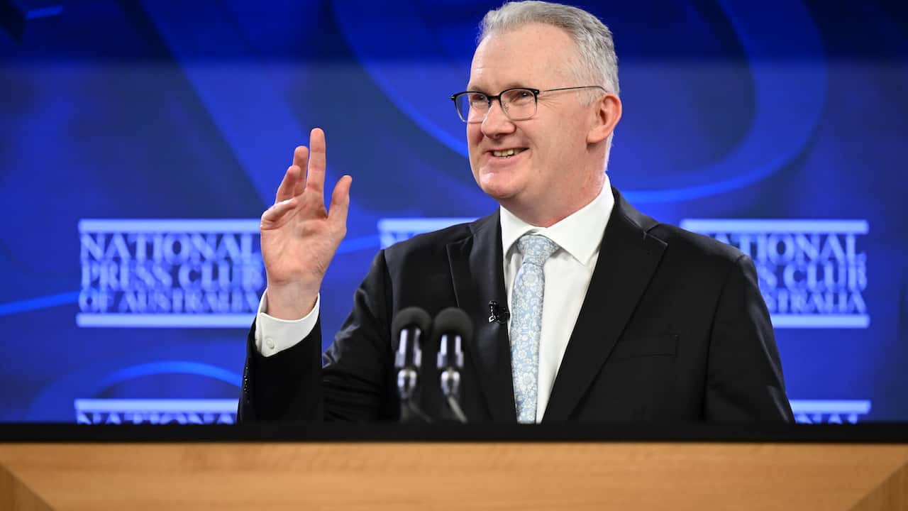 Tony Burke speaking in front of a blue mural that says National Press Club of Australia.