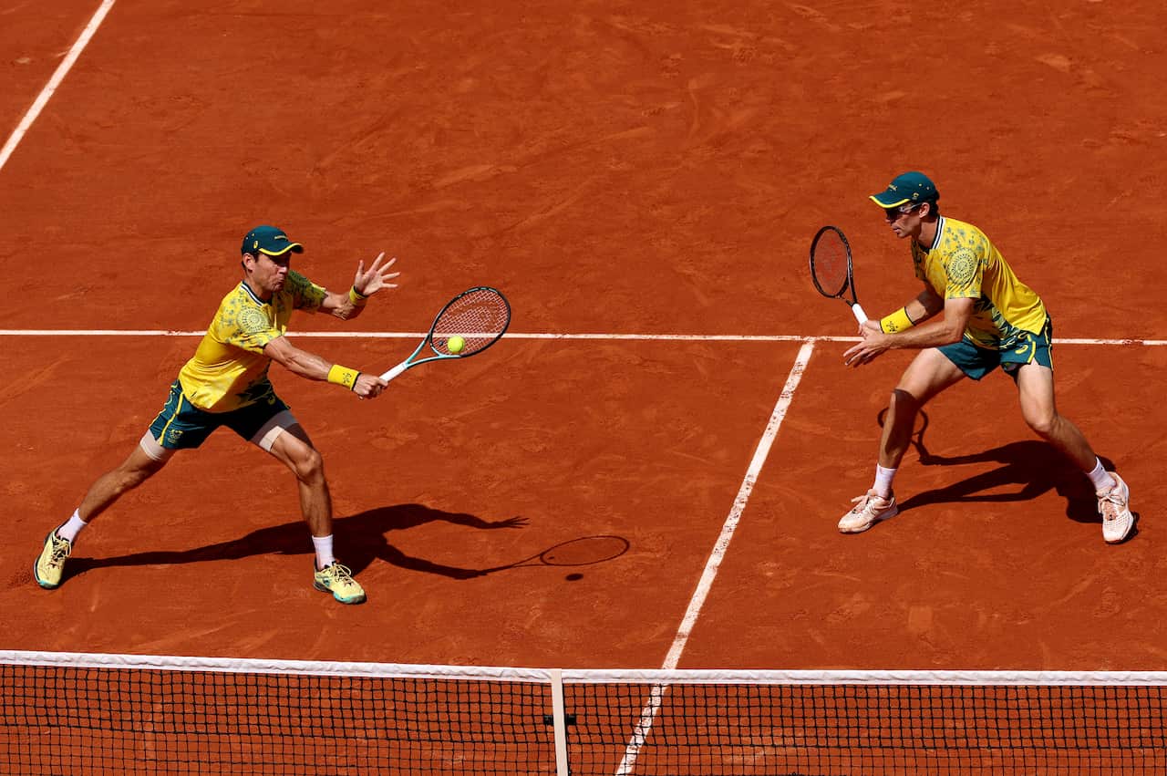 Two men play tennis side by side 