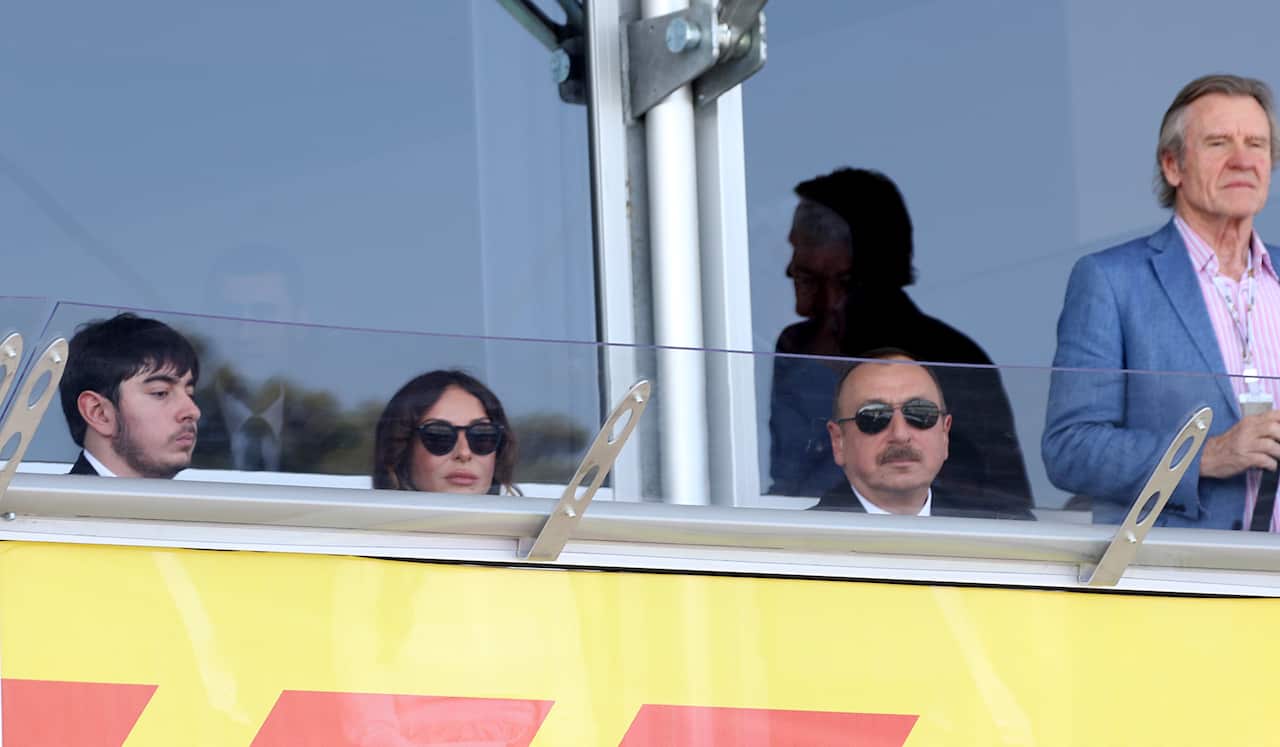 Four people look over guard rails at racing event.