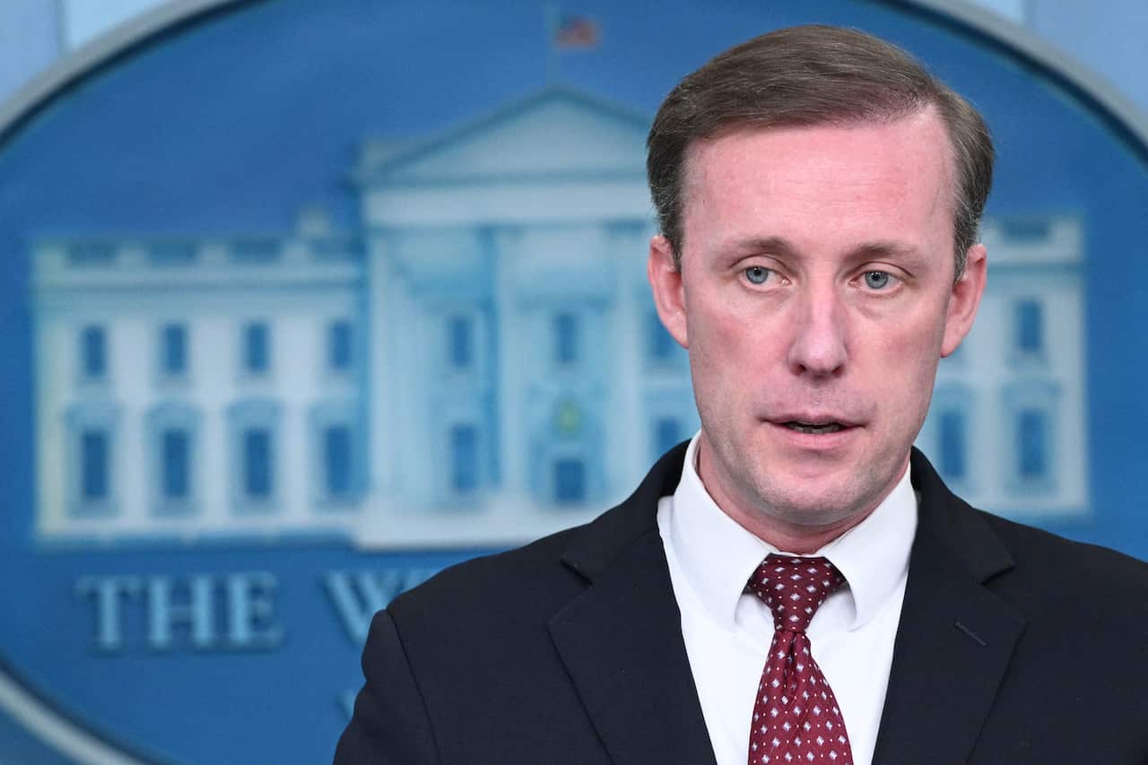A man in a black suit and red tie.