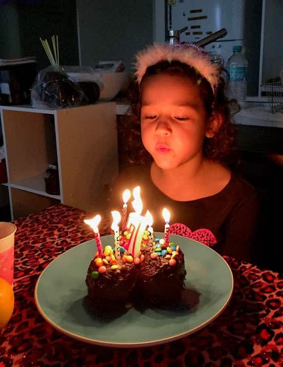 A young girl blowing candle out on her birthday cake.