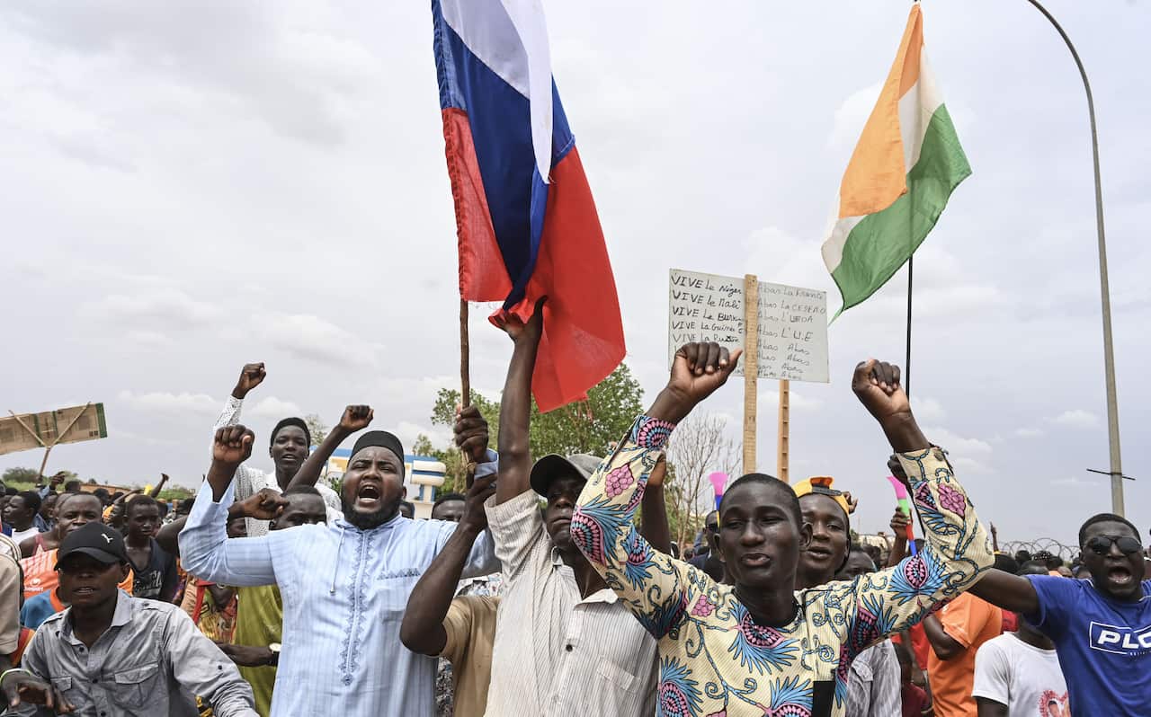 A group of men waving Nigerien and Russian flags at a demonstration 