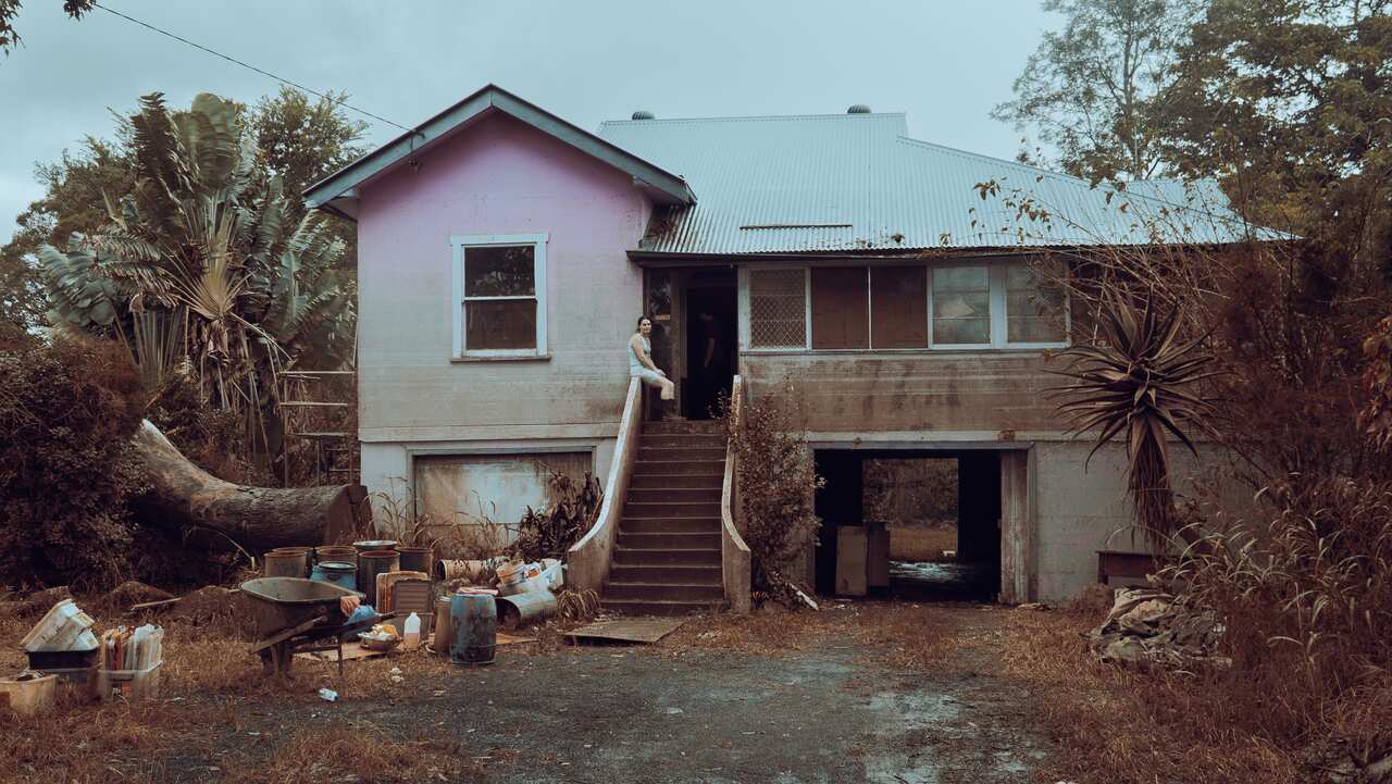 A woman is seen sitting on the steps of a flood-affected home in the city of Lismore, northern NSW.