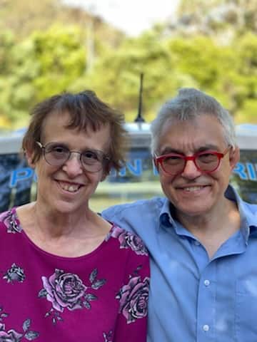 A couple embrace as they smile at the camera.