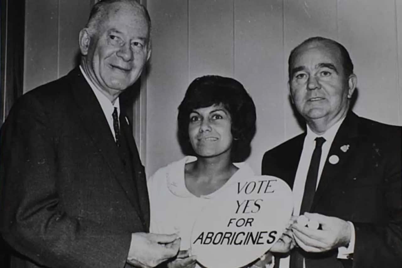 A woman standing between two men holding a sign reading 'vote yes for Aborigines'