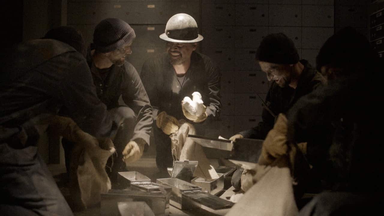 A gropu of men crowd around opened boxes in a vault. 