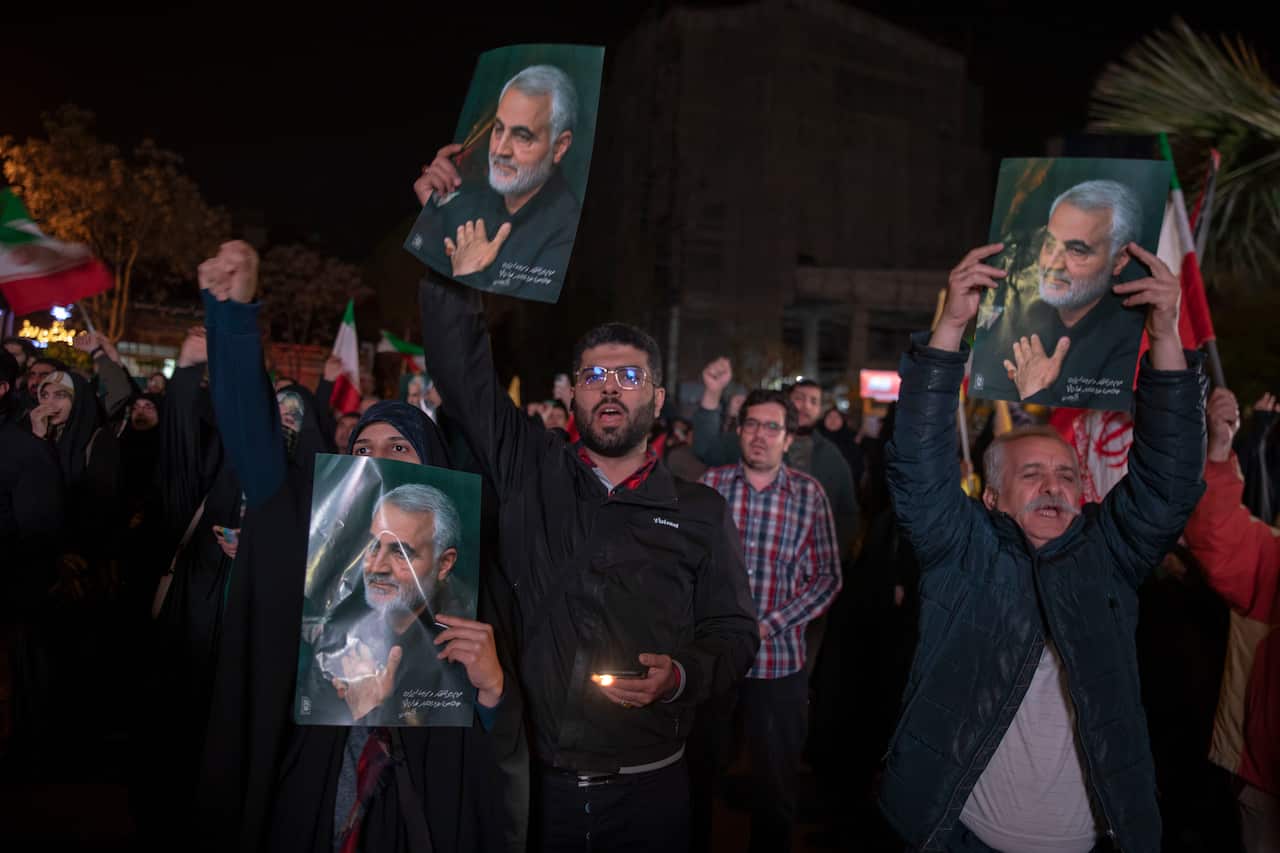People hold up photos and flags outside at night