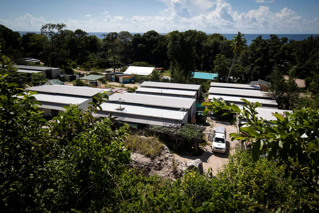 An aerial image of a facility with tiled roofs flanked by dense trees.