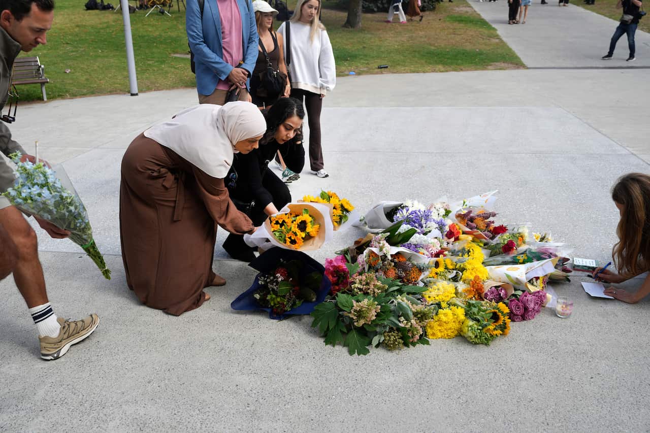 Two Muslim women lay flowers 