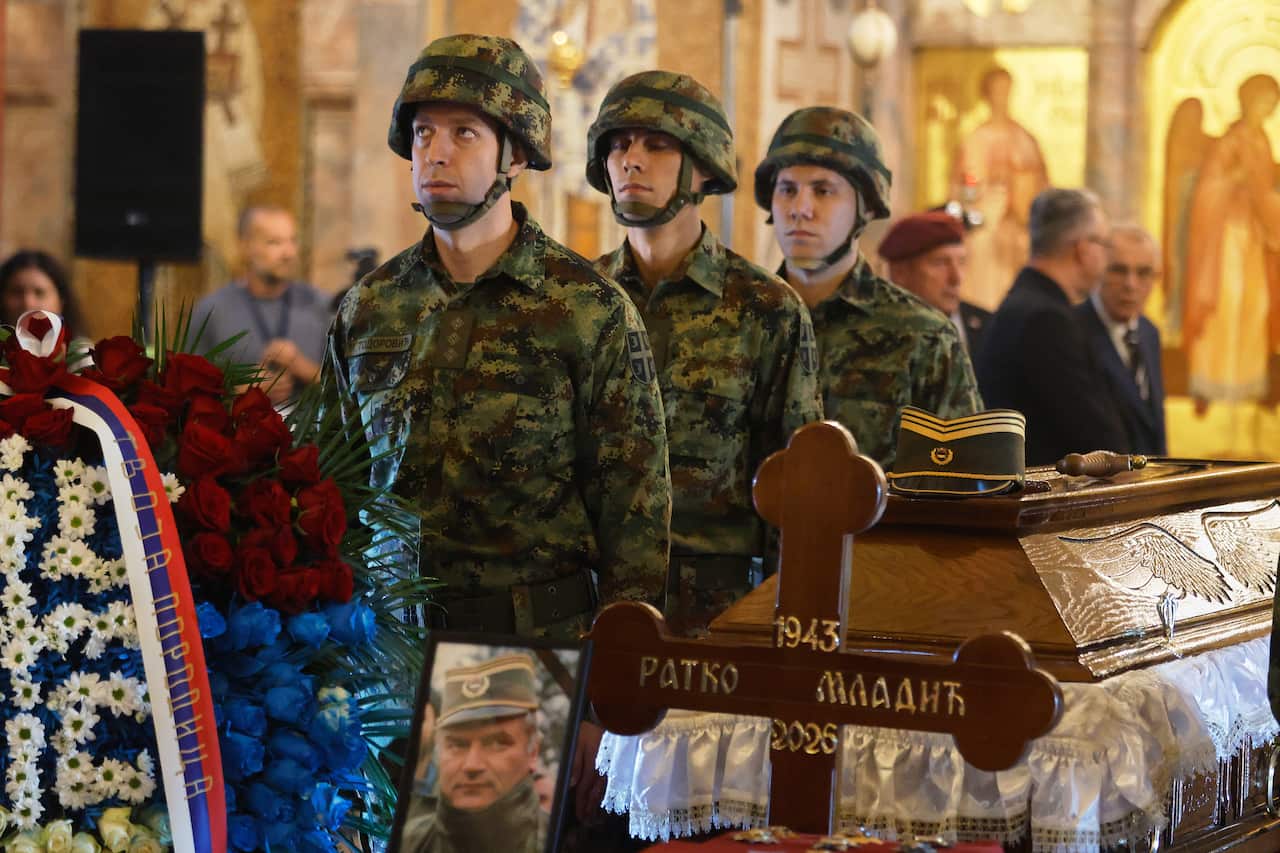 A group of soldiers in uniform stand next to a coffin in a church.