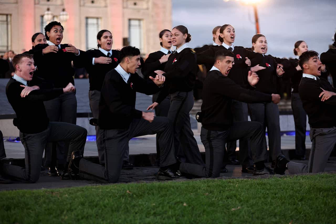 Several men and women standing together performing a dance. 