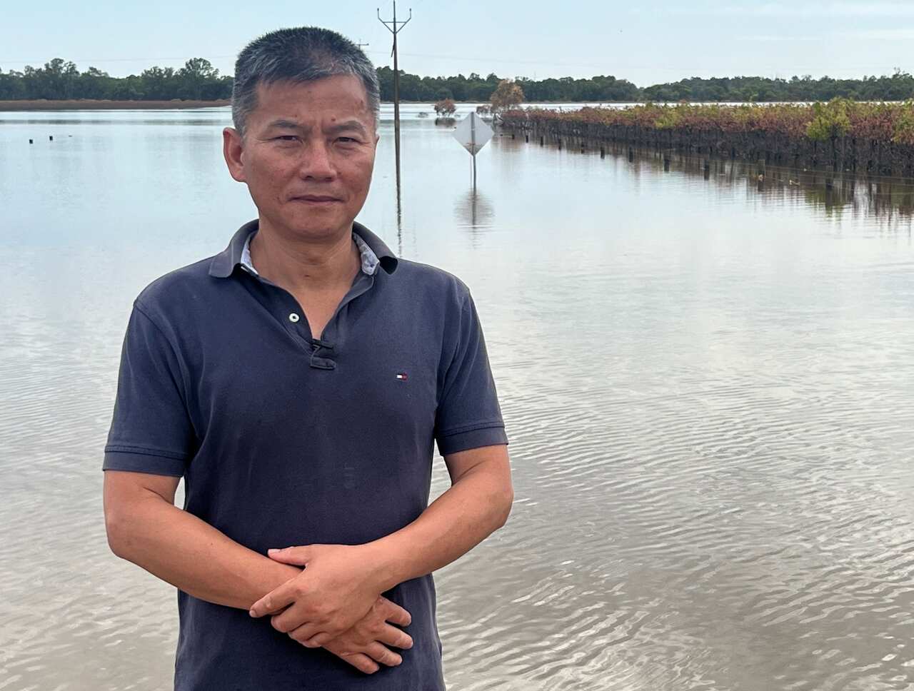 Lin Meiqing standing in his flooded field.
