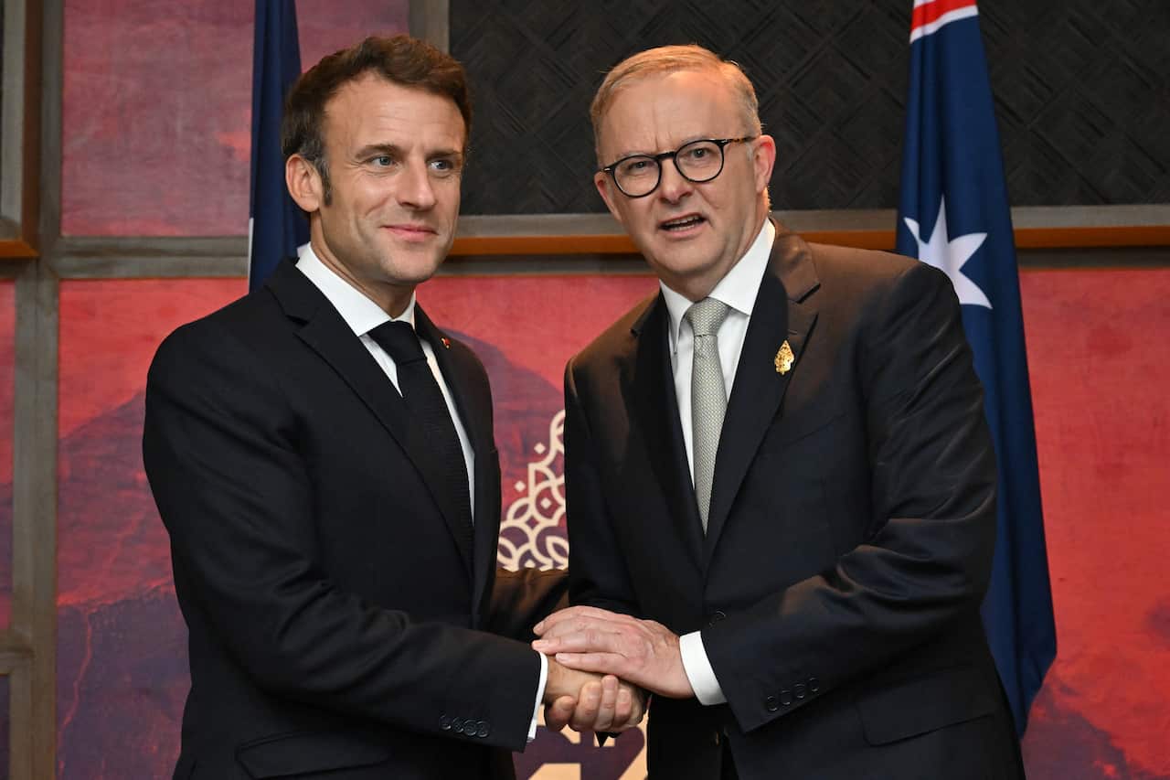 Two men wearing suits and ties standing next to each other.