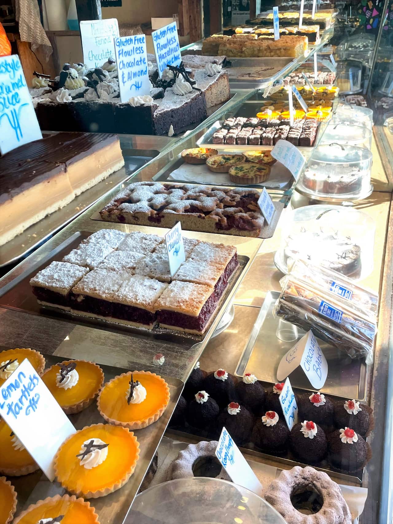 A shop window with rows of colourful cakes on shelves.