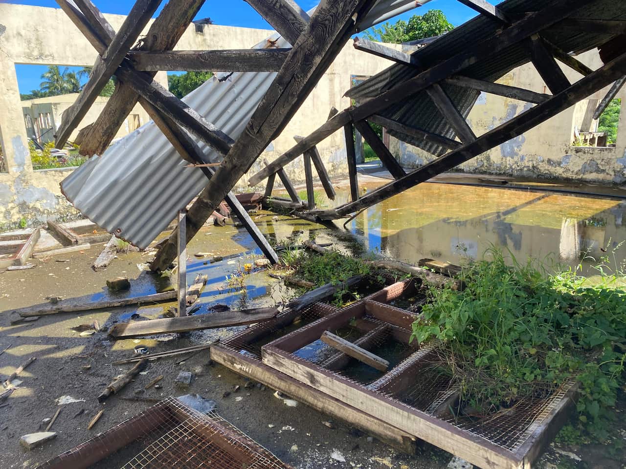 Roof caved in, leaving timber and wood hanging from above, while the ground is flooded