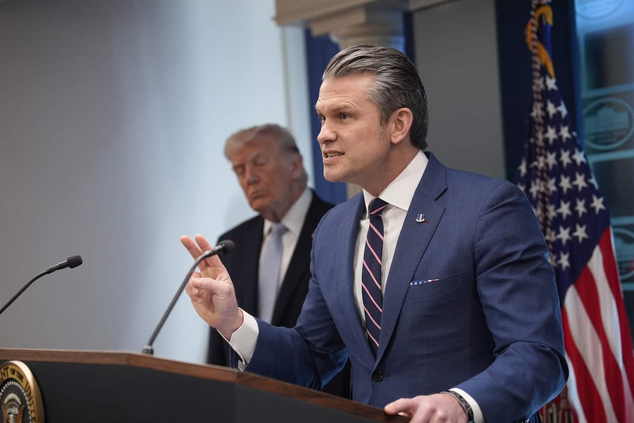 Two men in suits before a lecturn and American flag