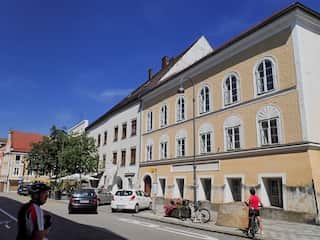 A yellow building with a rock out the front bearing an inscription.