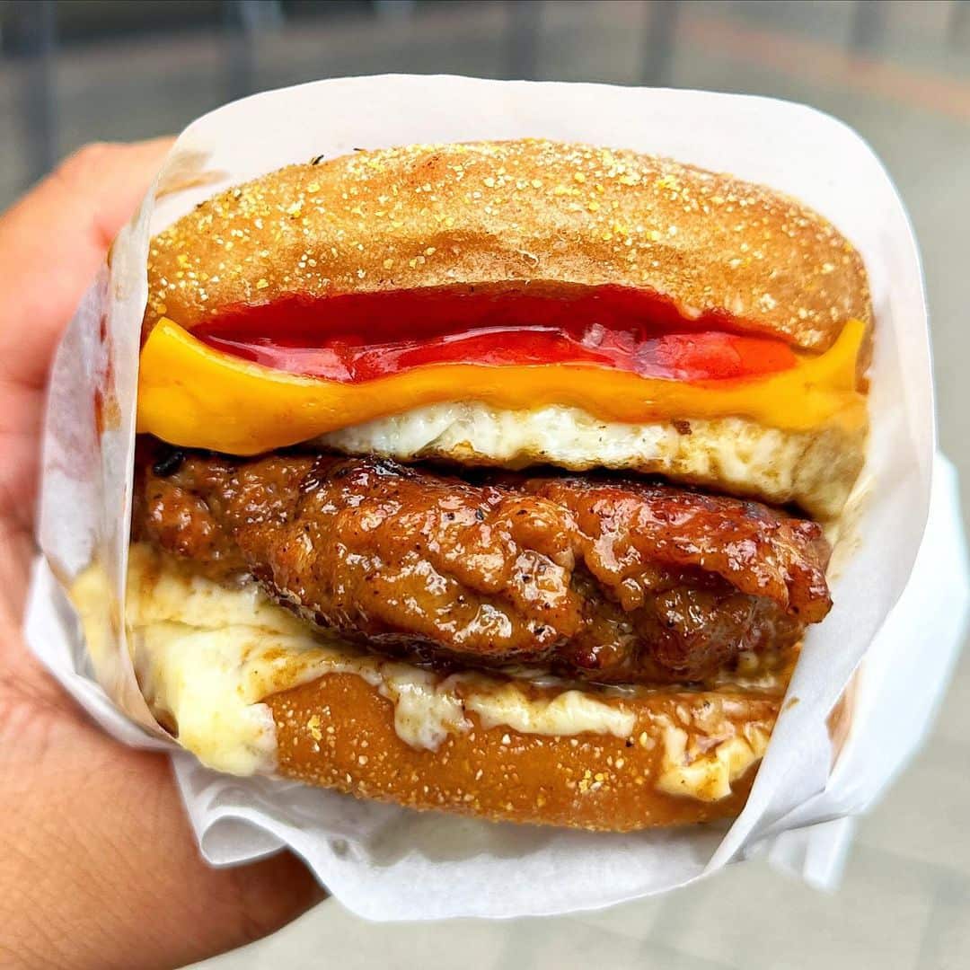 pandesal muffin with filling wrapped in paper in a hand