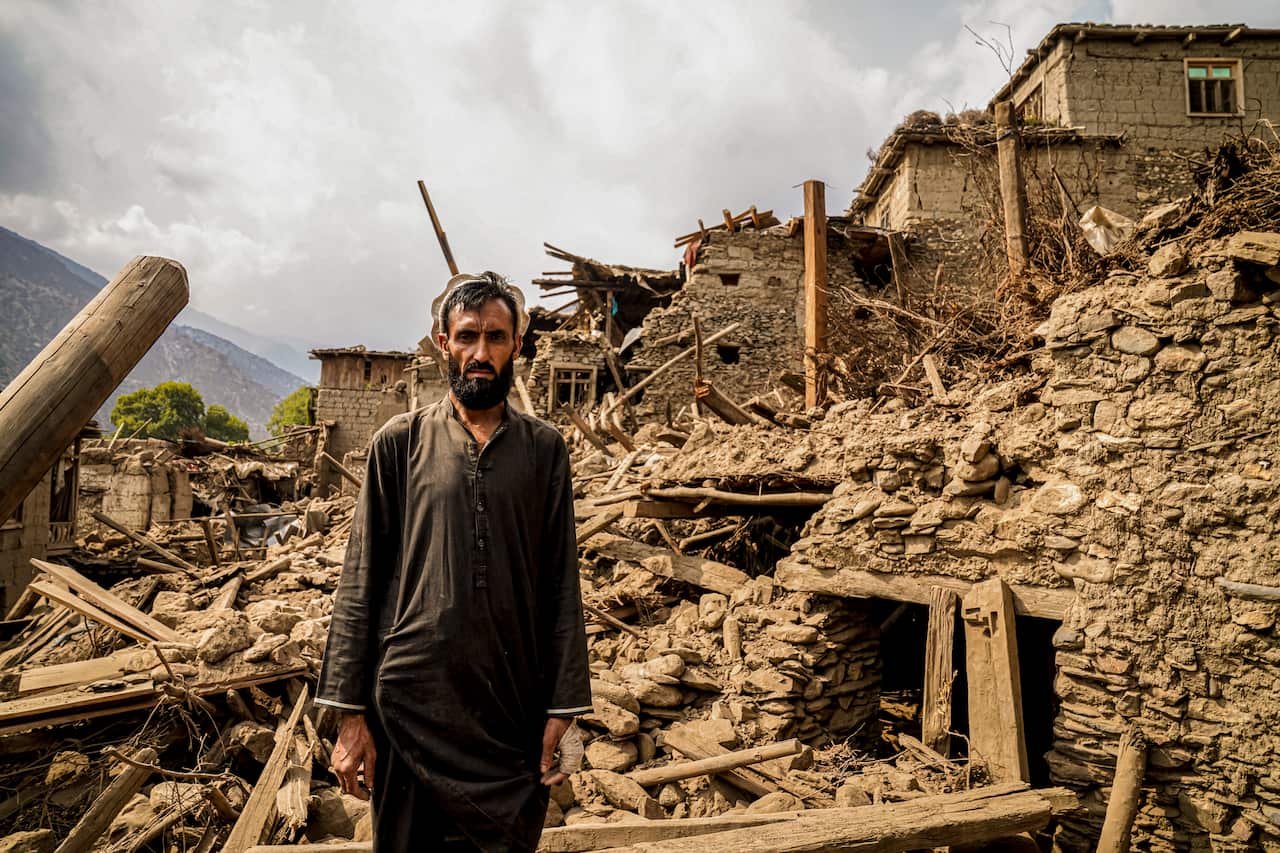 A man standing amidst the rubble of a severely damaged building.