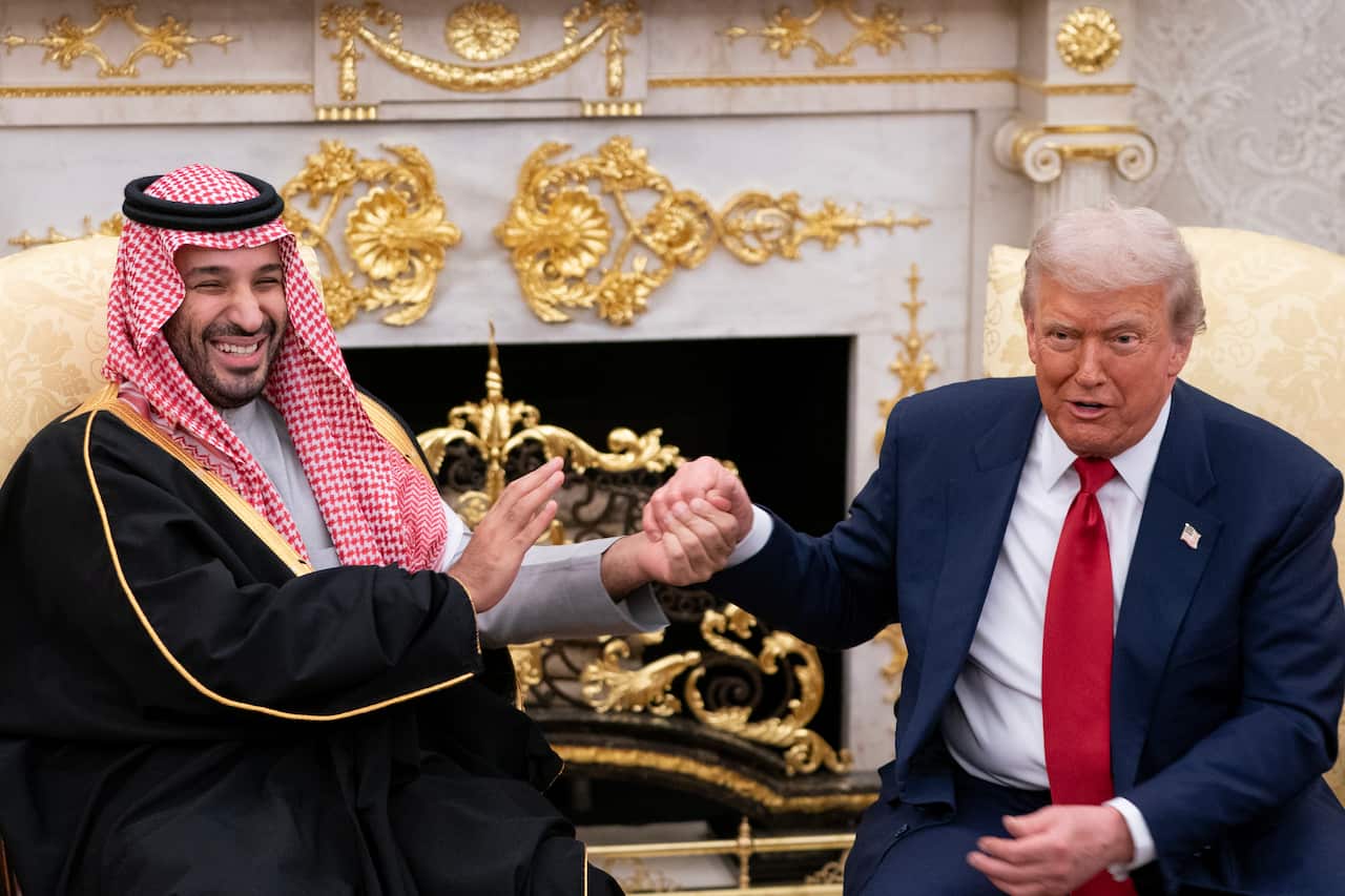 Two men shake hands in gold room