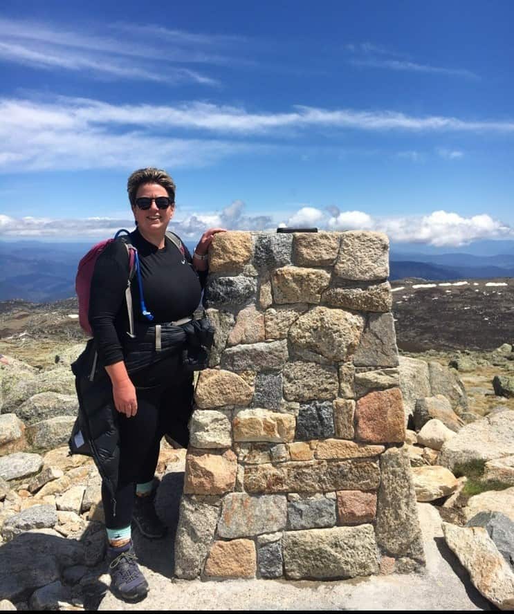 A woman wearing a backpack and hiking gear standing on a rocky mountain.