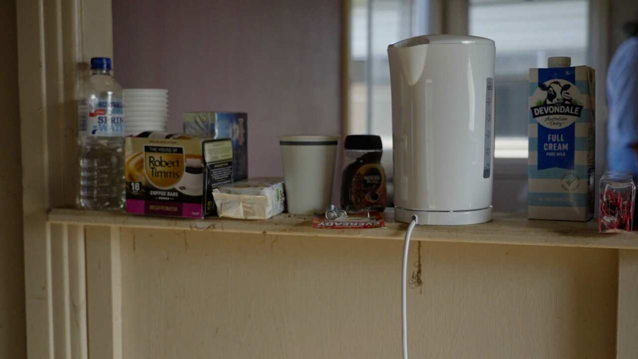 A picture of Gary's makeshift kitchen, with a single kettle, some teabags, some cups, a carton of milk and a bottle of water all sitting on a bench.