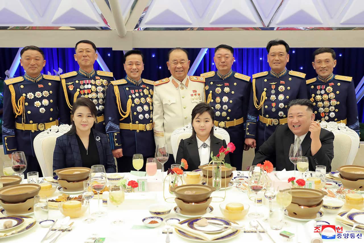 A woman, man and young girl pose for a photo during a banquet. 