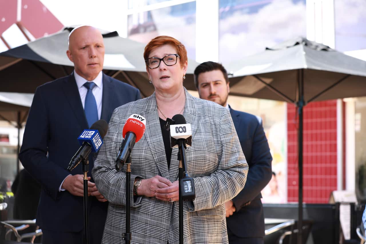 Marise Payne speaking in front of microphones, with Peter Dutton behind her.