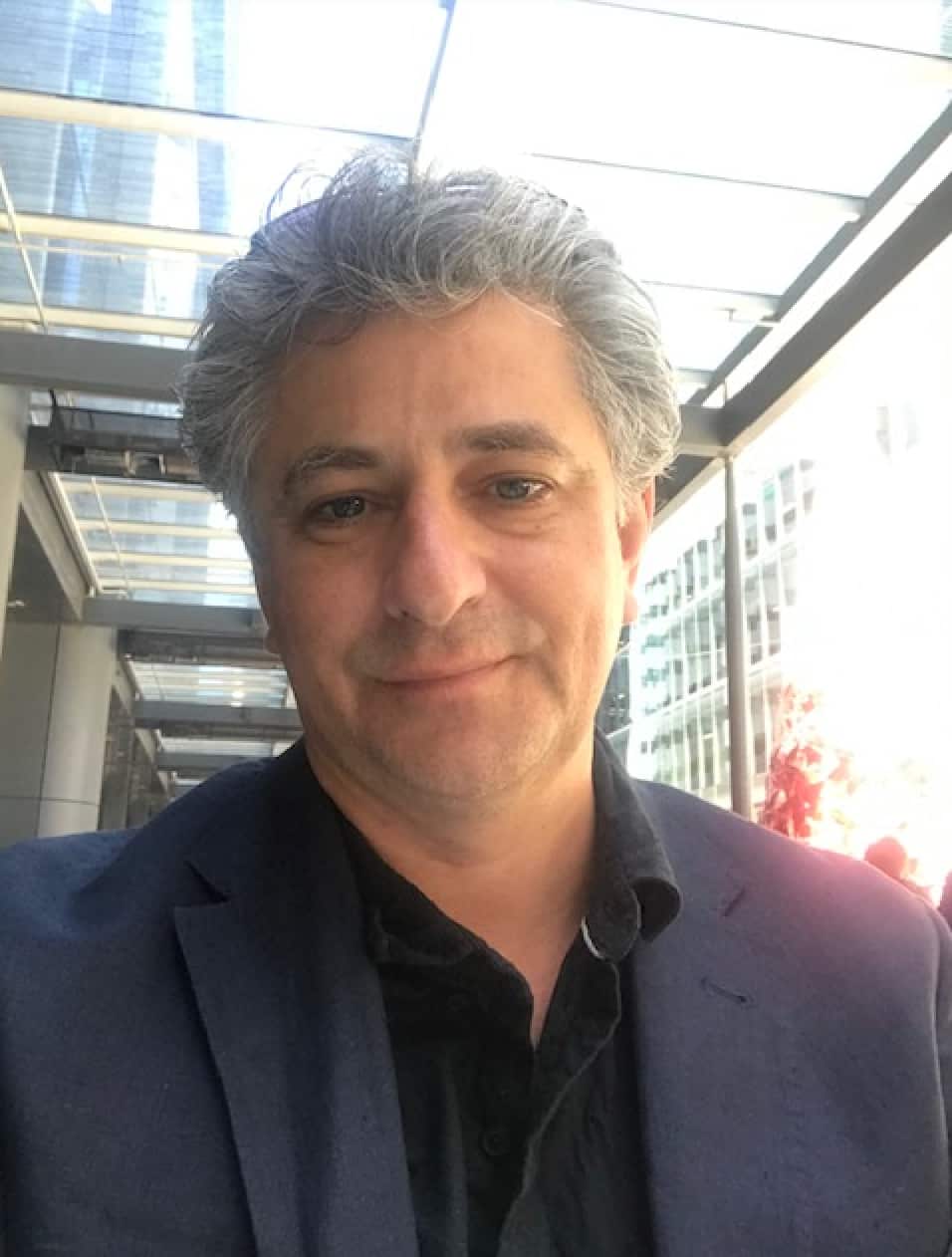 A man is pictured smiling for a photo wearing a suit.