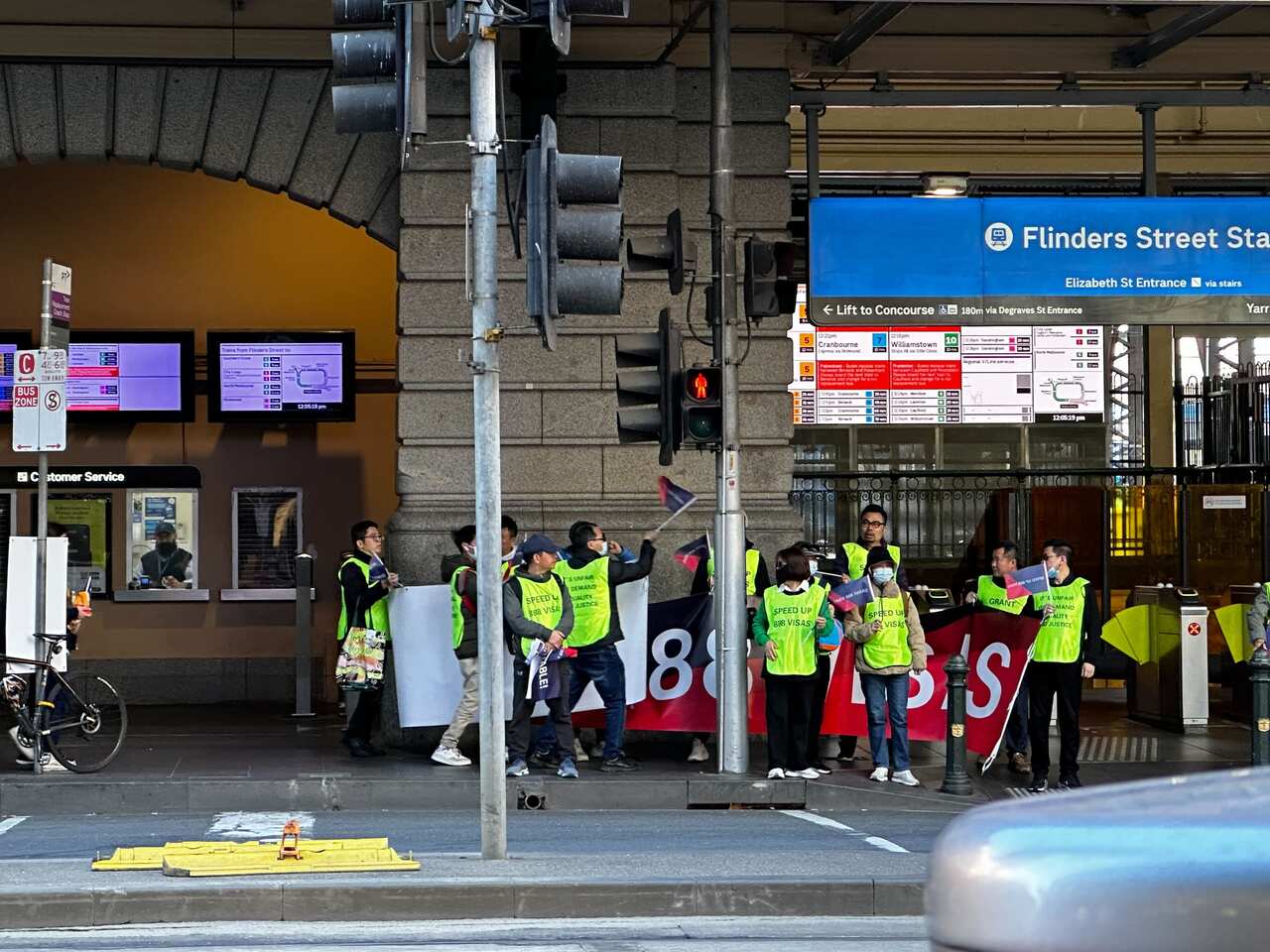 A group of protesters. Some are holding a banner that reads "speed up 888 visas".