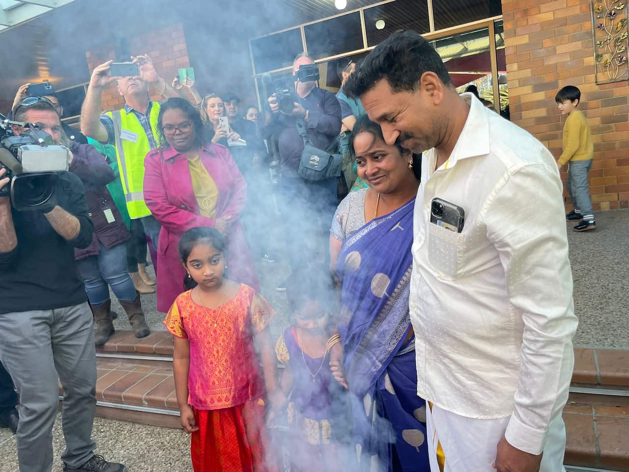 Nadesalingam family wearing traditional clothing surrounded by photographers