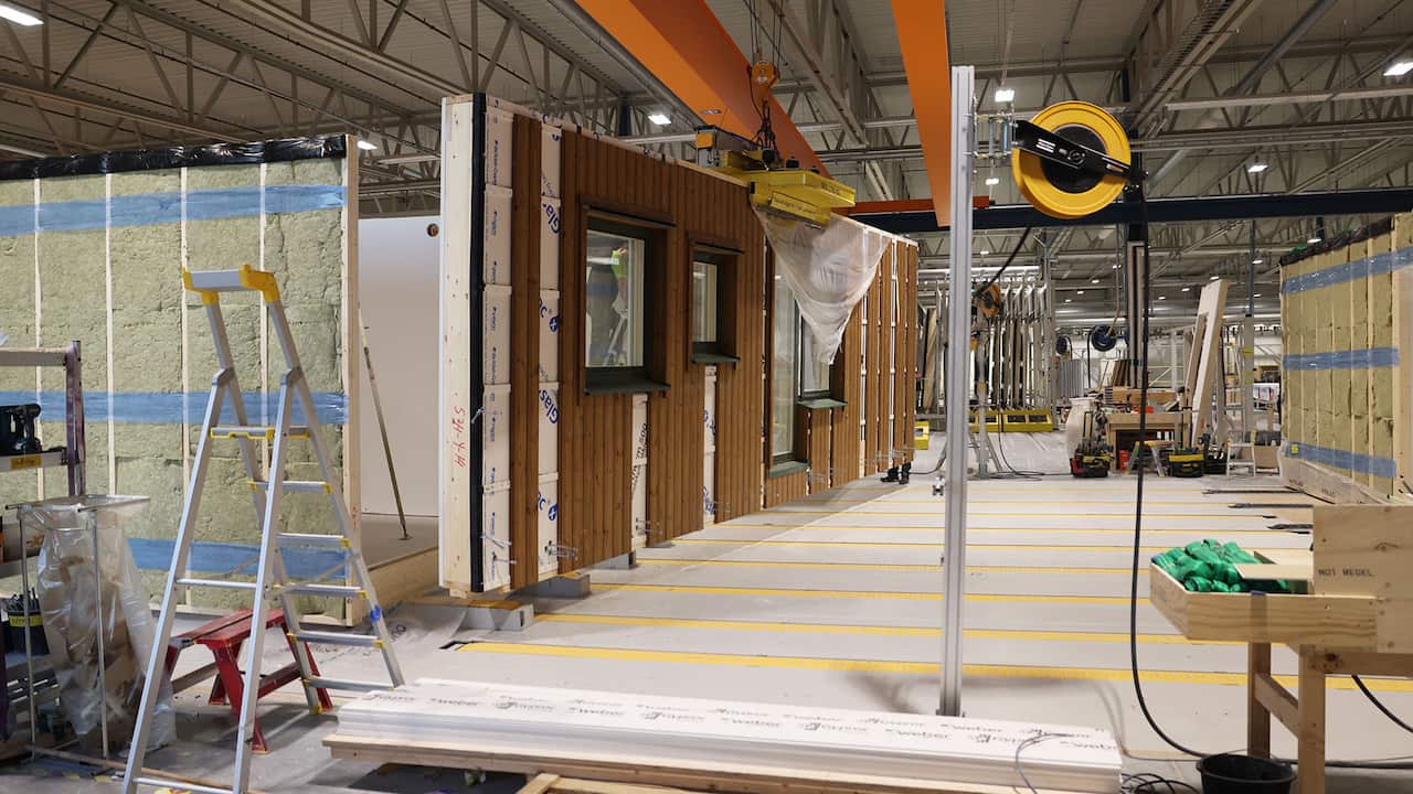 A factory interior showing partially constructed walls with a ladder and various equipment scattered around