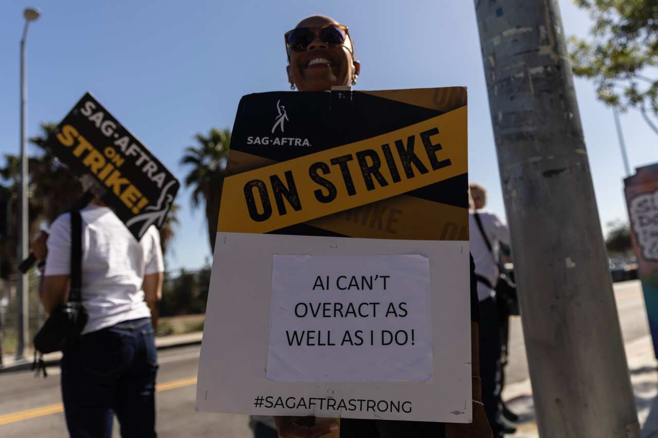 A person holds up a placard that says "AI can't overact as well as I do"