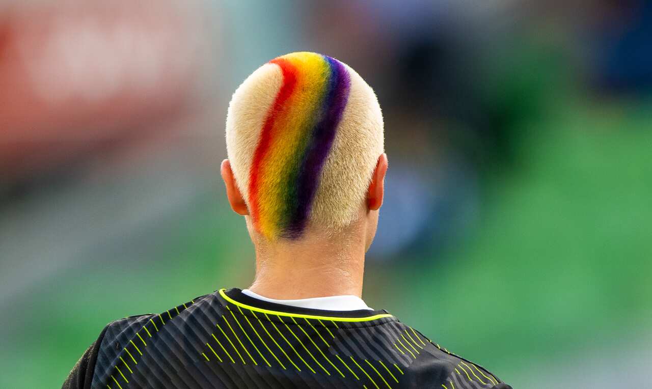 A goalkeeper with cropped blonde hair featuring a spray painted rainbow