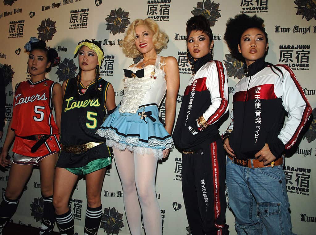 Five people pose on a red carpet in costumes. 