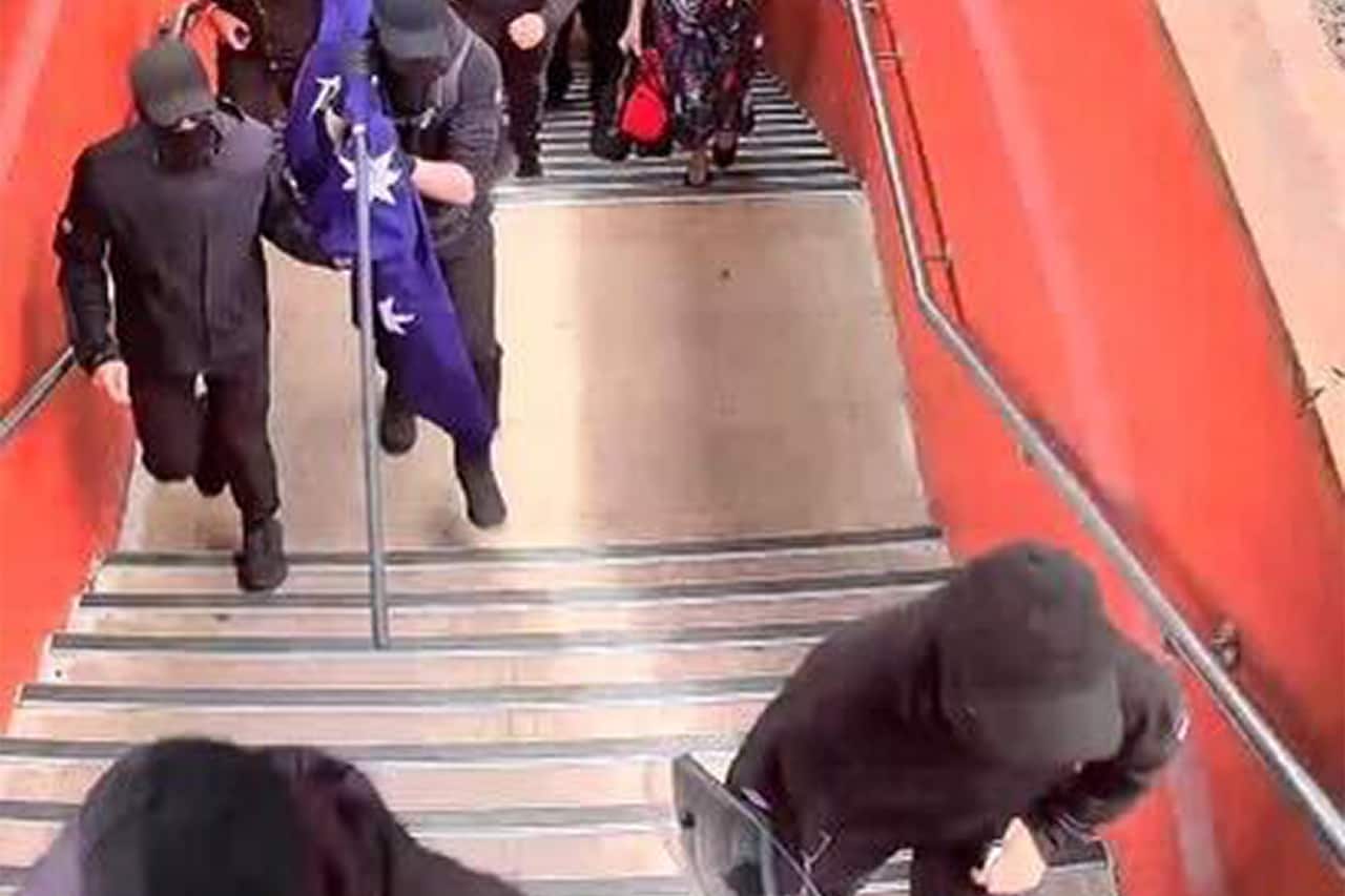 A group of people dressed in black climbing some stairs. Two are holding an Australian flag