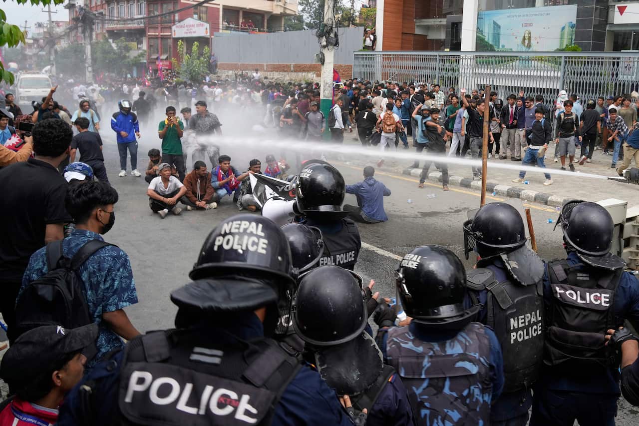 Police hitting protesters with a water cannon.
