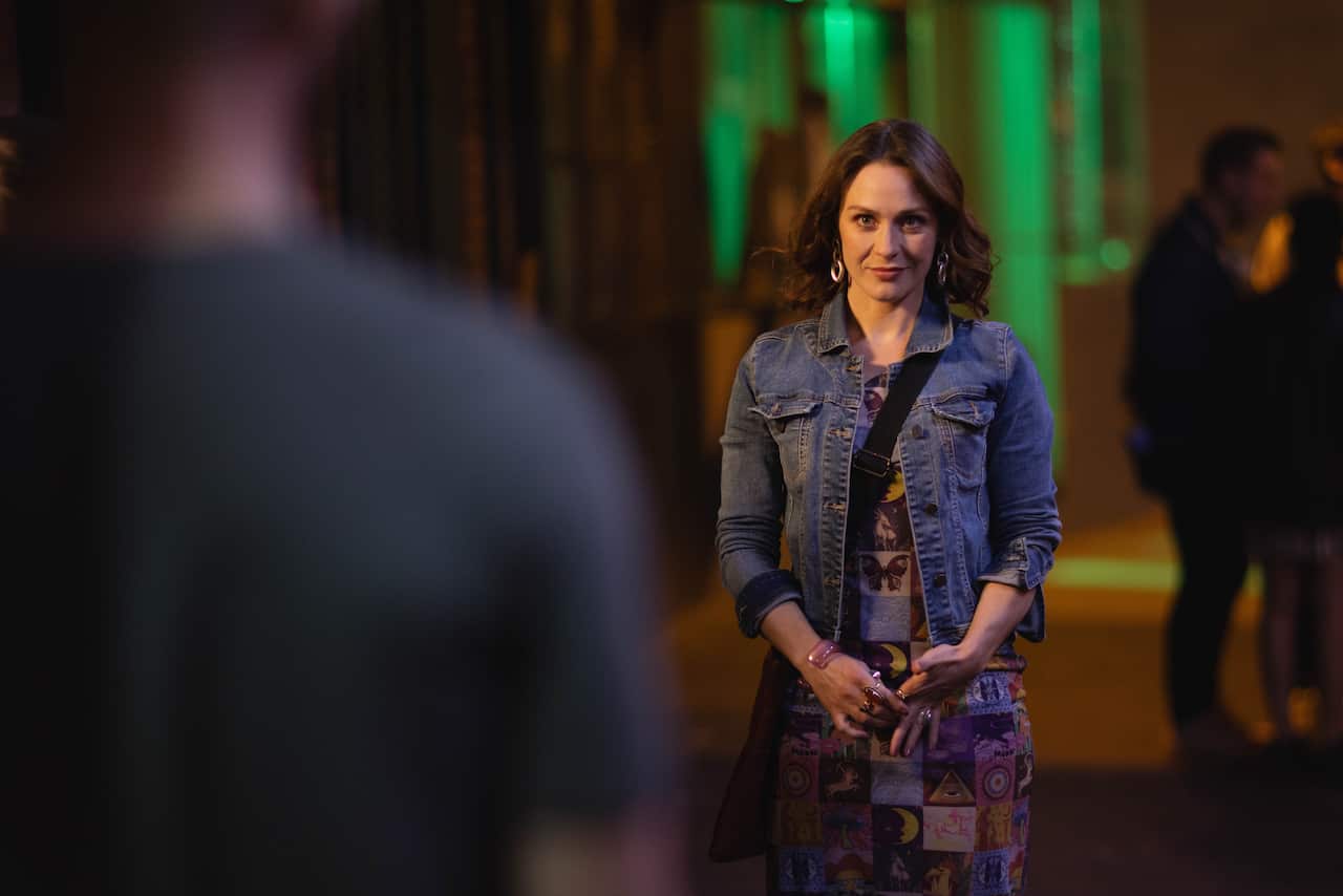 A woman walks down a street towards a man