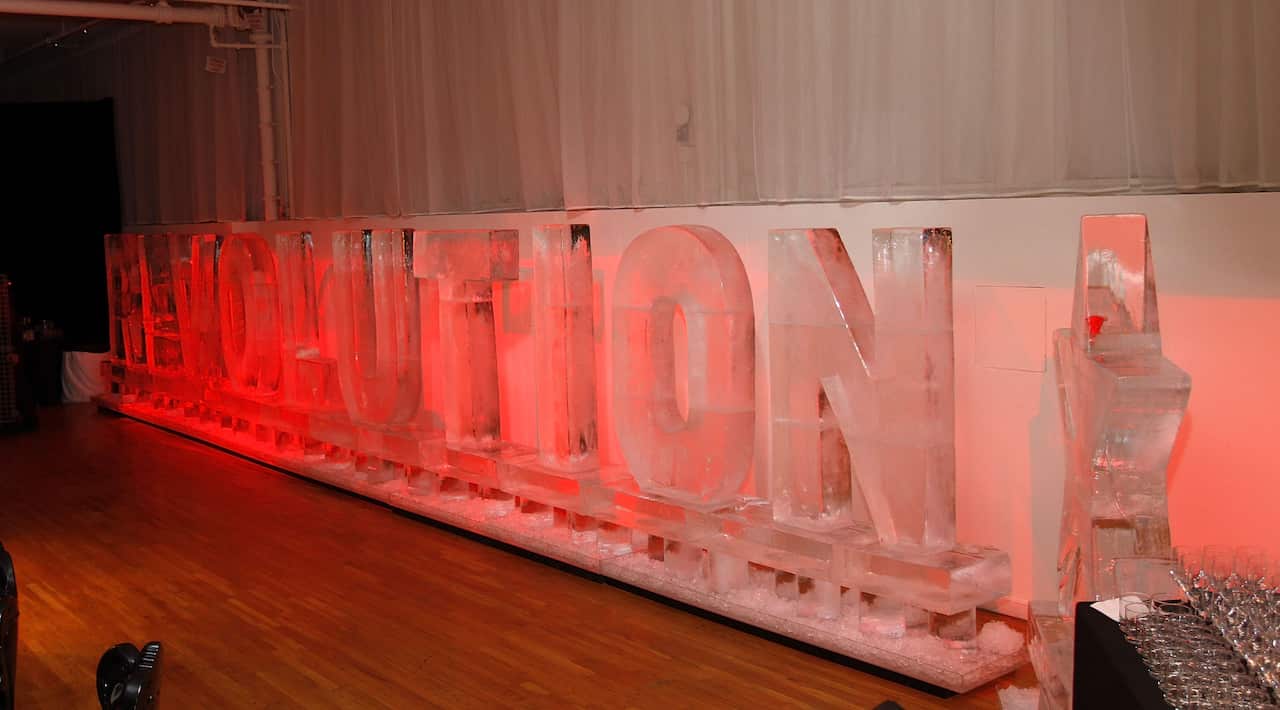 A large ice sculpture fills the wall of a room, shaped like the word Revolution and a star