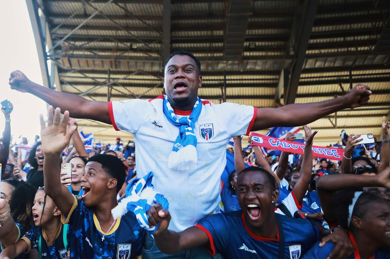 Fans celebrate in the stands of a football stadium.